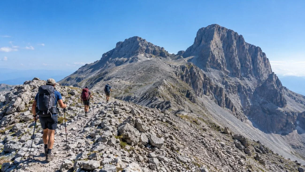 Hikers on a rocky ridge path high on Mount Olympus with summits ahead